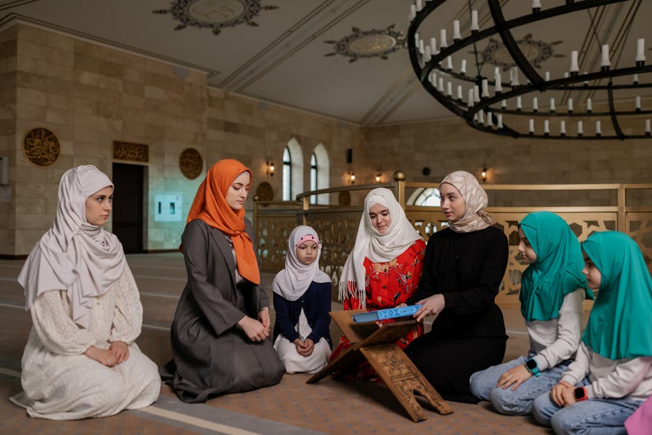 Women and children wearing headscarves praying inside a mosque for religious gathering.